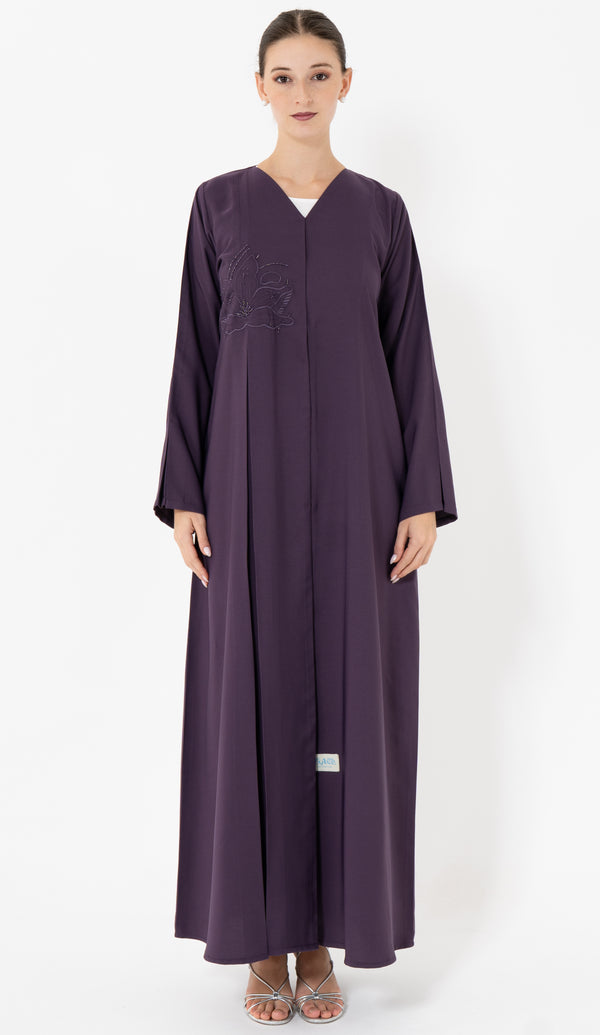 Woman wearing a long purple abaya on a white background